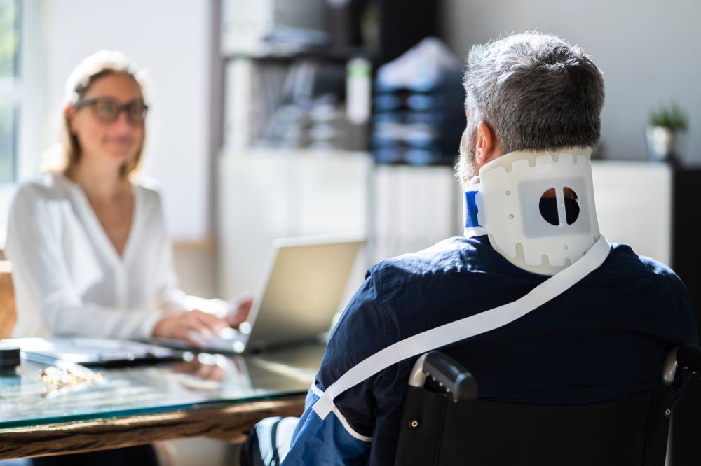 Client in a neck brace discusses options with personal injury attorney.