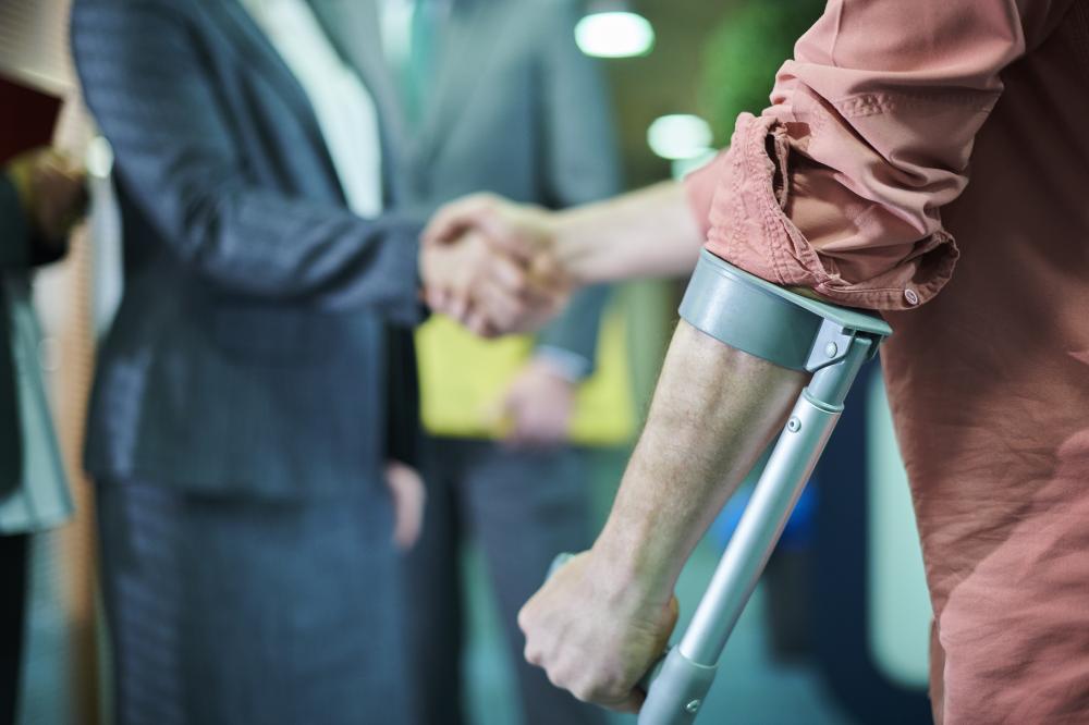 Man in crutches shakes hands while consulting with a personal injury attorney. 
